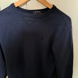 Mörkblå tröja från Polo Ralph Lauren - Säljer en stilren mörkblå tröja från Polo Ralph Lauren. Tröjan har en klassisk design med rund hals och långa ärmar. Perfekt för en avslappnad och snygg look. Tröjan är i storlek xl i barnstorlek men sitter ungefär som en xs. Säljs för den är för liten. Använd endast ett fåtal gånger så tröjan är i fint skick. Köptes för ca 1300 kronor