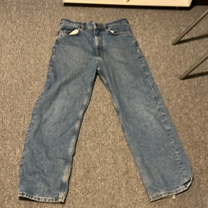 Blå jeans från GANT baggy 146-152 - Snygga blå jeans från GANT med klassisk femficksdesign. De har en rak passform och är tillverkade i slitstarkt denim. Perfekta för en avslappnad stil.