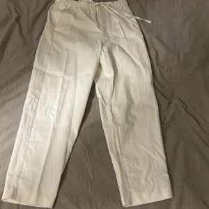 Vita linne byxor från Zara - vita linne byxor från Zara med carrot fit. De har en elastisk midja med snörning för extra komfort. Perfekta för en stilren look.