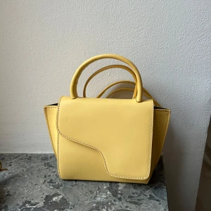 Gul handväska från ATP - Snygg gul handväska från ATP atelier. Mer åt ljusgul i färgen skulle jag säga.  Kommer inte till användning, använd typ 1 gång, därför säljer jag. 