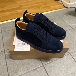 louboutin - Snygga mörkblå sneakers i mocka med klassisk röd sula från Christian Louboutin. Skorna har snörning och en stilren design som passar perfekt för en trendig look.