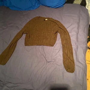Brun croppad tröja - Säljer en brun, stickad croppad tröja med lång ärm. Perfekt för en stilren och avslappnad look. Passar bra till både jeans och kjol.