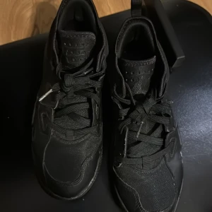Svarta Nike Air Jordans - Säljer ett par svarta Nike Air Jordans med klassisk design och snörning. Skorna har en stilren look med Jumpman-loggan på sulan och baksidan. Perfekta för dig som vill ha en ikonisk sneaker i garderoben.