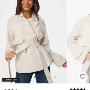 Beige trenchcoat med bälte - Snygg beige trenchcoat med knappar och bälte i midjan. Jackan har en klassisk krage och långa ärmar med knappar vid ärmsluten. Perfekt för en stilren look.