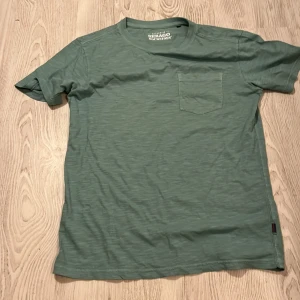Grön t-shirt från Sebago - Säljer en stilren grön t-shirt från Sebago med en praktisk bröstficka. Perfekt för en avslappnad look. Gjord i mjukt material för extra komfort. Passar bra till jeans eller shorts!.Aldrig använt fick i julklapp men var för stor storlek S