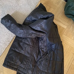 Svart jacka från Hope - Säljer en stilren svart jacka från Hope. Jackan har en quiltad design med knappar och långa ärmar. Perfekt för en minimalistisk look. 🖤