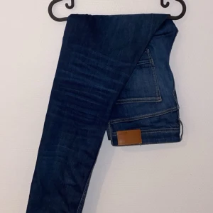 Mörkblå jeans  - Snygga mörkblå jeans med klassisk femficksdesign och en läderpatch på baksidan. Perfekta för en stilren look.
