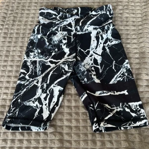 Svartvita mönstrade shorts - Snygga svartvita shorts med ett unikt mönster som påminner om marmor. Perfekta för en cool och avslappnad stil. De har en bekväm passform och är gjorda i ett stretchigt material.