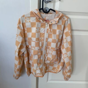 Rutig vår jacka från Zara 🧡 - Säljer en snygg orange och vit vårjacka med blommönster. Jackan har en dragkedja framtill och en praktisk huva. Perfekt för vår och sommar! 