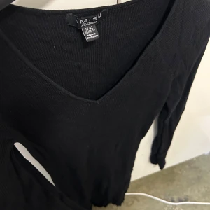 Klänning - Säljer en klänning från MISU med v-ringning. Klänningen har långa ärmar och en figurnära passform, perfekt för en elegant look. 