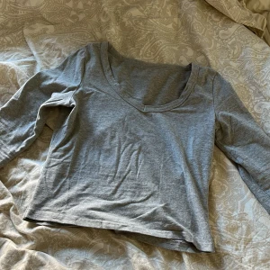 Grå långärmad tröja - Säljer en enkel och stilren grå långärmad tröja med v-ringning. Perfekt för en avslappnad look. Tröjan är mjuk och bekväm, idealisk för vardagsbruk eller pyjamaströja💕nästan aldrig använd