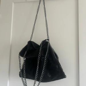 Svart väska med kedjedetaljer - Säljer en Stella McCartney liknande väska. Snygg och rymlig! Vet ej märket