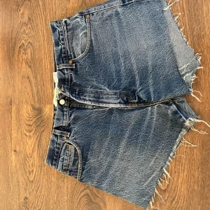 Blå jeansshorts från Levi's - Säljer ett par klassiska blå jeansshorts från Levi's med fransiga kanter. De har en hög midja och är tillverkade i 100% bomull. W36 men är något små, skulle säga att de är W32. Säljer för 200kr💗