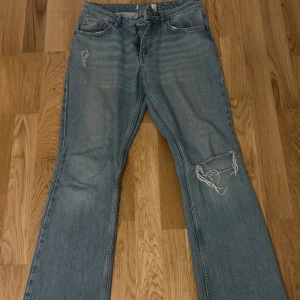 mid waist jeans - Mid waist jeans med hål under fickan och ett hål i knät, lappen på byxorna har halva gått av