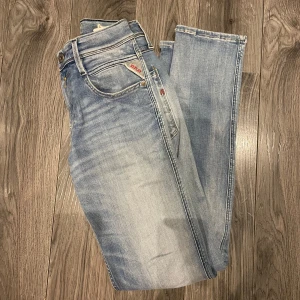 Ljusblå jeans från replay - Snygga ljusblå jeans från replay i modellen Anbass med en klassisk femficksdesign och knappgylf. Perfekta för en avslappnad stil.                 Storleken är 30/32.