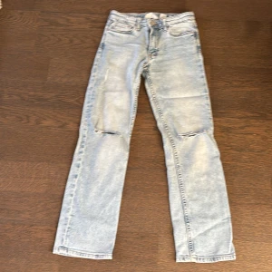 Ljusblå jeans från H&M - Säljer ett par ljusblå jeans från H&M med justerbar midja och låg midja. De har en straight passform och klassisk femficksdesign. Perfekta för en avslappnad stil.