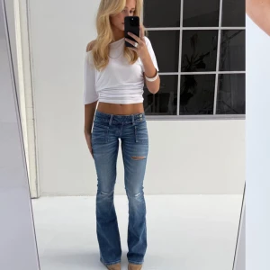 Lågmidjade bootcut jeans - Säljer dessa populära snygga blå bootcut jeans med hål. De har en låg midja och helt slutsålda & prislappen kvar (gina young 14+.)