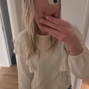 Beige tröja med volangdetaljer från Zara - Säljer en stilren beige tröja från Zara med volangdetaljer på axlarna. Tröjan har långa ärmar och en rund halsringning. Perfekt för en trendig look! 💫 den är i storlek 164 men passar utmärkt för en xs eller s också! Använt sparsamt 🫶🏻💞