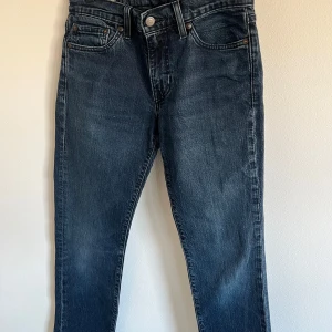 Levi's Premium Jeans - Snygga Levi's Premium jeans i en klassisk blå färg. Dessa jeans har en modern passform och är perfekta för en stilren look. De har en knappgylf och fem fickor, vilket ger en tidlös design.