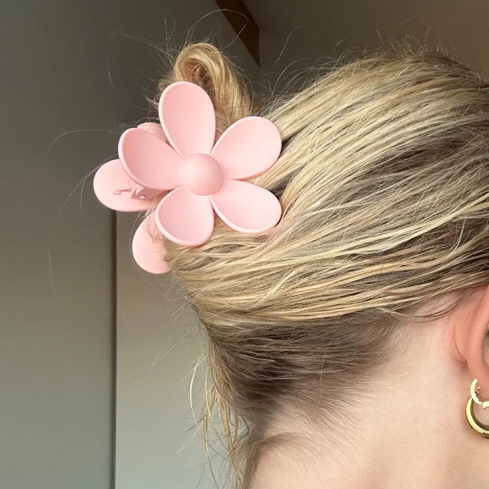 Söt rosa hårklämma i form av en blomma. Perfekt för att ge en lekfull touch till din frisyr. Klämman är lätt att använda och håller håret på plats.. Asusteet.