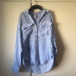Blåvit randig skjorta från Amisu XS - Snygg blåvit randig skjorta från Amisu i storlek XS. Skjortan har klassisk krage, långa ärmar, två bröstfickor och knappar framtill. Perfekt för en chill och stilren look. Tillverkad i mjuk bomull som känns skön mot huden.