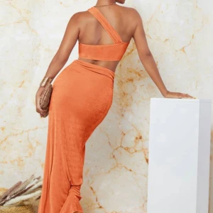 Orange set  med slits och omlott - Snygg orange set med omlott-detalj och hög slits framtill. Setet  har en asymmetrisk one shoulder-design och är figurnära med twistad midja. Perfekt för dig som vill sticka ut med en trendig och vågad look.