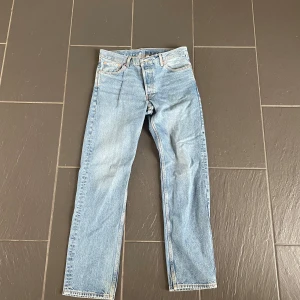 Ljusblå Weekday  jeans  - Klassiska Weekday jeans i ljusblå denim med rak passform. Byxorna har fem fickor, knappgylf och normal midja. Perfekta för en avslappnad och tidlös stil. Ikonisk läderpatch bak i midjan och snygg vintagekänsla.