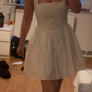 Vit kort klänning med fyrkantig urringning - Säljer min fina klänning med V-formad midja från Gina Tricot som är använd i 2 timmar. Ordinarie pris 499kr. Slutsåld just nu. Storleken är 38 men passar en 36a också som jag är. Tog endast storlek 36 för att jag ville att den skulle vara lite längre. Är 163cm lång.