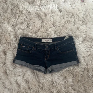 Lowaist jeansshorts från Hollister - Snygga mörkblå jeansshorts från Hollister med klassisk femficksdesign och uppvikta benslut. Shortsen har kontrastsömmar och broderad logga på fickan fram samt detaljerade bakfickor. Pris går att diskutera. Storlek S