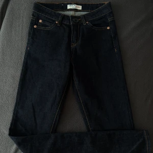 Mörkblå jeansbyxor Denim Allience - Snygga mörkblå jeansbyxor från Denim Allience med klassisk femficksdesign och kontrastsömmar. Byxorna har rak passform och är tillverkade i slitstarkt jeanstyg. Perfekta för dig som gillar en stilren och tidlös look.