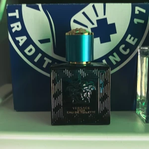 Versace Eros Eau de Toilette - Versace Eros Eau de Toilette i en stilren, fyrkantig flaska av mörkblått glas med Medusa-huvudet ingraverat på framsidan. Flaskan har ett metalliskt turkost lock med gulddetaljer som ger en lyxig känsla. Perfekt för dig som gillar exklusiva dofter. Ungefär lite mer än hälften kvar.