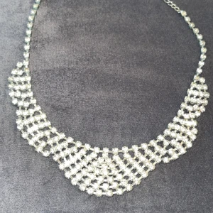 Silver halsband  - Ett riktigt snyggt halsband med glittrande stenar i ett brett, flätat mönster. Halsbandet är i silverfärg och har en kedja med justerbar längd. Perfekt för att lyfta vilken outfit som helst med extra bling och wow-känsla.