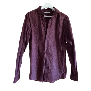 Vinröd paisleymönstrad skjorta Jack & Jones - Snygg vinröd skjorta från Jack & Jones Premium med paisleymönster i svart. Skjortan är långärmad, har klassisk krage och knäppning framtill. Tillverkad i 100% bomull för en skön känsla. 