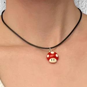Super Mushroom Halsband Super Mario Smycke Nintendo Choker - Supersvampen från Super Mario som halssmycke! 🍄 Trädd på svart tråd, justerbar 40-45 cm. Berlocken är ca 1,6 x 1,6 cm. Perfekt för den som älskar Nintendo och mushroom kingdom. 