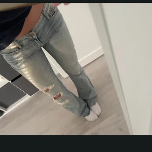 Ljusblå bootcut jeans med slitningar - Säljer ett par ljusblå bootcut jeans från Espress jeans med slitna detaljer och hål på knäna. Jeansen har låg midja. Perfekta för en trendig look. W 38,5cmm och L 86cm