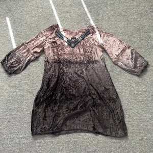 Brun sammetsklänning U by Uldahl - Superfin brun sammetsklänning från U by Uldahl med v-ringning dekorerad med pärlor och trekvartsärmar. Klänningen har en smockad midja och är i kort modell, perfekt för dig som gillar unika detaljer och mjuka material.