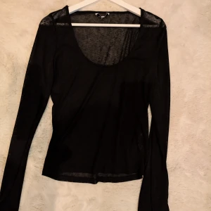 Svart långärmad topp Bubbleroom - En svart, tunn och långärmad topp från Bubbleroom med rundad urringning. Toppen är enkel och stilren, perfekt att styla med jeans eller kjol. Materialet känns lätt och smidigt mot huden.