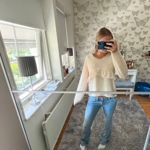 Vit blus med volang och prickar - Supersöt vit blus med diskret prickigt mönster och volangdetalj. Långärmad med lätt transparent tyg. Perfekt till jeans eller kjol💕