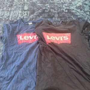 Levi's t-shirts med röd logga - Två klassiska t-shirts från Levi's, en i svart och en i blått, båda med den ikoniska röda Levi's-loggan framtill. T-shirtsen är kortärmade och har en normal passform. Perfekta för en avslappnad och cool look. 59 kr för båda, 39 kr styck.