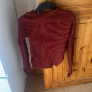 Mörkröd ribbad stickad tröja H&M - Säljer en mörkröd ribbad stickad tröja från H&M med bredare krage och lång ärm. Tröjan har en snygg, figurnära passform och är perfekt för lager-på-lager. Superenkel att styla till jeans eller kjol för en chill look.