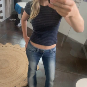 Mörkblå randig croppad topp - Säljer en mörkblå och svart randig croppad topp med korta ärmar och rund hals. Tight passform som sitter snyggt och framhäver figuren. Perfekt till jeans eller kjol för en chill och stilren look.