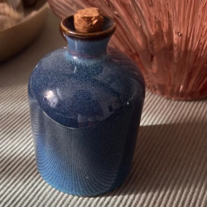 Blå keramikflaska med kork - Unik parfymflaska i blå keramik med glaserad yta och rundad form. Flaskan har en smal hals och försluts med en klassisk korkpropp. Perfekt som dekorativ detalj eller för att förvara din favoritdoft.