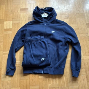 Mörkblå Nike club zip-hoodie + byxor - Säljer en mörkblå hoodie från Nike. Perfekt för chill dagar eller träning. Matchande byxor finns också för full tracksuit. Inte använd mycket. 399kr för bara hoodien, 299kr för bara byxorna.