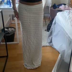 Vit långkjol med rutigt mönster  - Säljer en vit långkjol med diskret rutigt mönster. Kjolen är lätt transparent och har en rak passform som sitter snyggt i midjan
