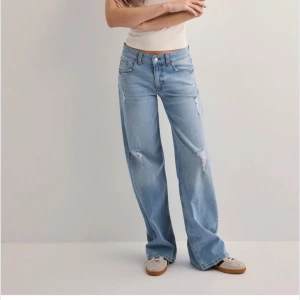 Ljusblå wide jeans med slitningar - Säljer ett par ljusblå jeans med breda ben och snygga slitningar på låren och knäna. Jeansen har klassisk femficksdesign och normal midja. Perfekta för en avslappnad och trendig look. Använda en gång!