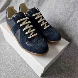 Maison Margiela gats - Snygga sneakers från Maison Margiela i mörkblått skinn och mocka med beige snörning och gummisula. Klassisk siluett med rund tå och diskreta detaljer. Perfekta för dig som gillar stilrena och trendiga skor. Mest intill helt oanvända! Vid funderingar är det bara höra av sig!.. Våga buda