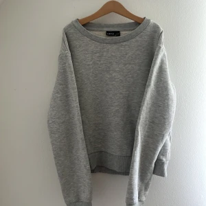 Grå sweatshirt från LMTD, storlek 158-165 - Enkel och stilren grå sweatshirt från LMTD i storlek 158-164. Tröjan har rund halsringning, ribbade muddar vid ärmslut och nederkant samt en mjuk insida. Perfekt för en avslappnad och bekväm look.
