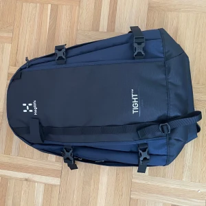 Mörkblå ryggsäck Haglöfs Tight Large - Säljer en mörkblå och svart Haglöfs Tight Large ryggsäck med flera smarta fack och justerbara remmar. Den är helt ny används två gånger eller mindre. Väskan har vadderad rygg, robusta spännen och dragkedja. Perfekt för skola, äventyr eller träning. Rymmer mycket och är riktigt bekväm att bära.