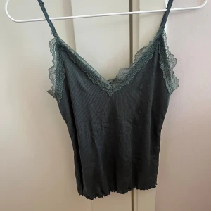 Grön ribbad linnetopp med spets Amisu - Supersnygg grön ribbad linnetopp från Amisu med smala axelband och v-ringning. Toppen har fina spetsdetaljer längs urringningen och ärmlös design. Köpt för 69kr på new yorker säljer för 30kr men kan förhandlas! 💕
