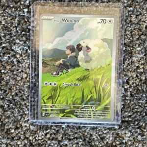 Hop's Wooloo - Samlarkort från Pokémon med coolt motiv av Hop och Wooloo i naturen. Perfekt för dig som älskar Pokémon och vill utöka din samling med en unik och färgglad karta. Kortet är skyddat i plastfodral och passar både nya och erfarna samlare.